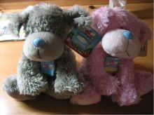 Two fluffy stuffed toy dogs, one grey and the other pink