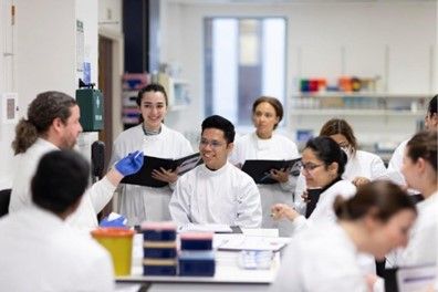 Licamm group of nine researchers holding folders being taught in a lab