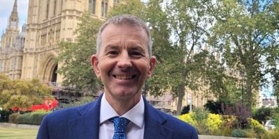 Mark Monwilliams in a suit smiling at the camera outside the House of Commons.