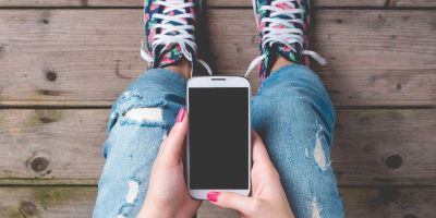 A teenager holding their phone in their hands.