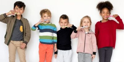 A line of five children brushing their teeth.