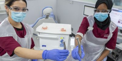 Two dental surgery students holding electric dental handpieces