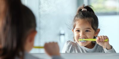 Young child brushing teeth in a mirror