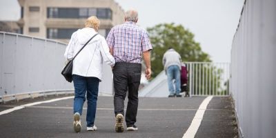 An older couple walking across a bridge