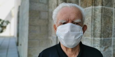 Image of elderly man wearing a white face covering.