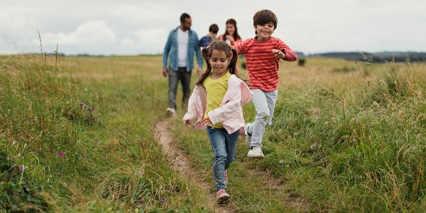 An image of children and adults walking through a field representing carers and service users