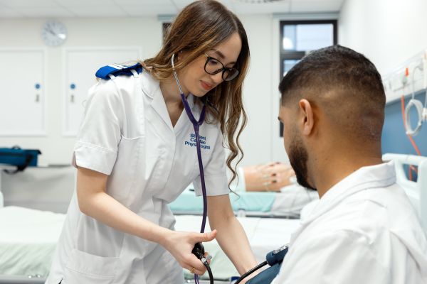 Female checking blood pressure of male patient