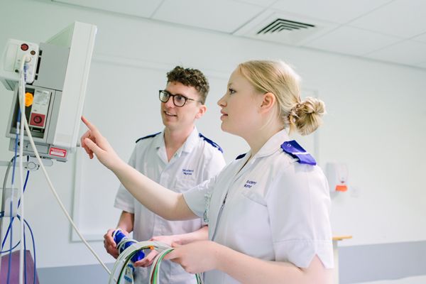 Two students look at a monitor in a hospital setting.