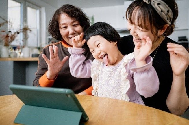Child making faces with parents watching screens