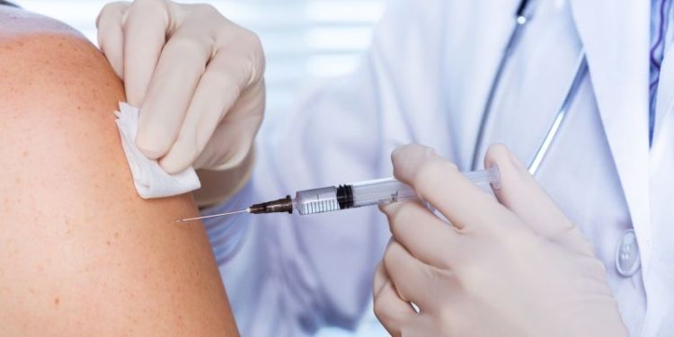 A nurse holding a needle to someone's arm