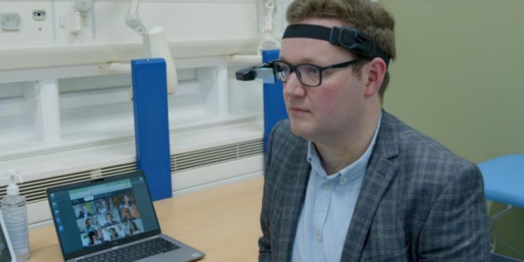 A doctor sat at a desk wearing a headset in a virtual patient consultation