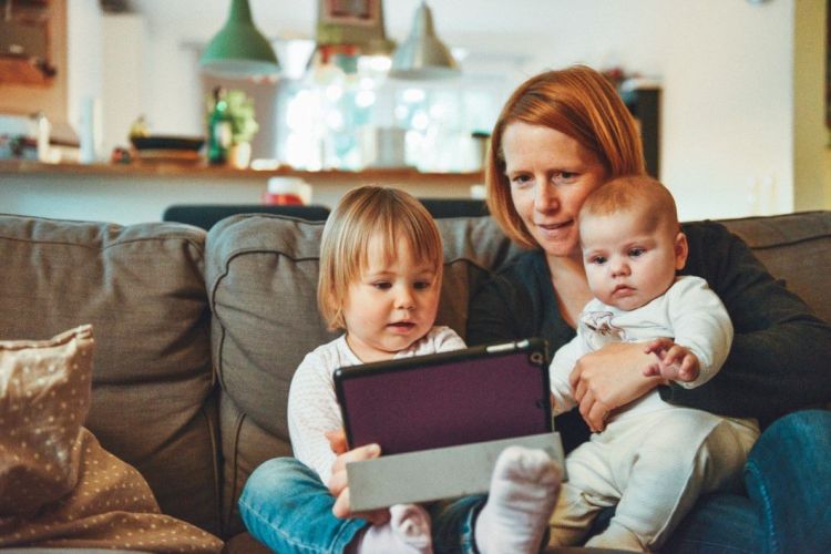 toddler and baby watching an ipad with mum