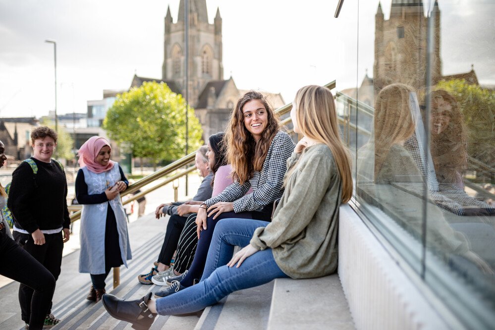 Students sitting outside a building chatting