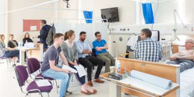 Medical students sat around a patients bed in training