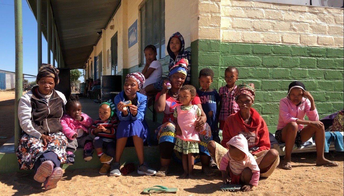 Parents and children sitting outside a building looking into the camera